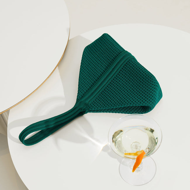 The Party Pouch in Emerald Green laid down on a table.