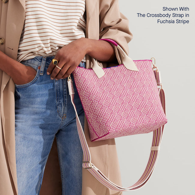 The Lightweight Petite Tote in Fuchsia Geo, carried from the top handle by a model, shown from the front with the Crossbody Strap in Fuchsia Stripe.