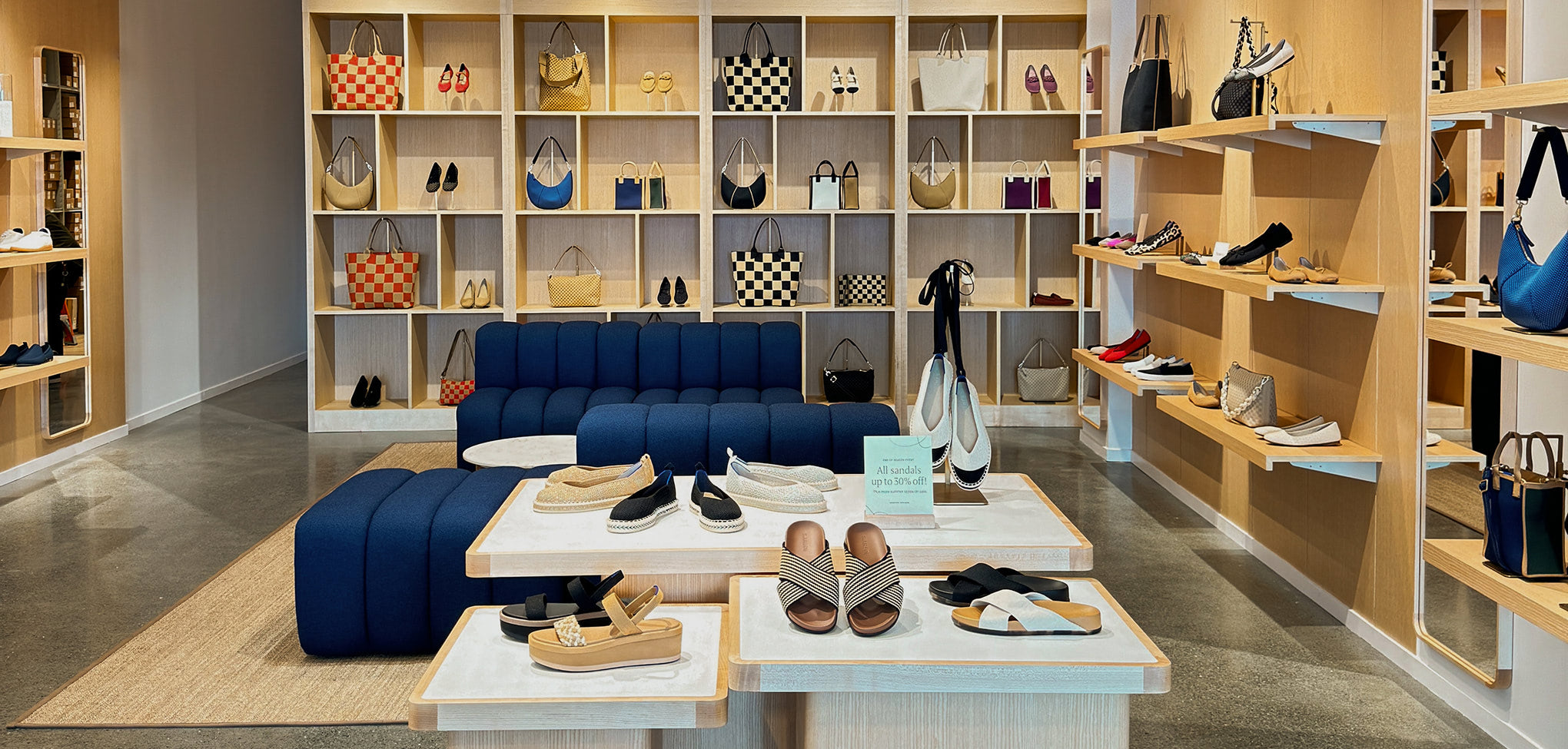 Rothy's interior store with blue sectional sofa, tables, and shelves displaying shoes and handbags.