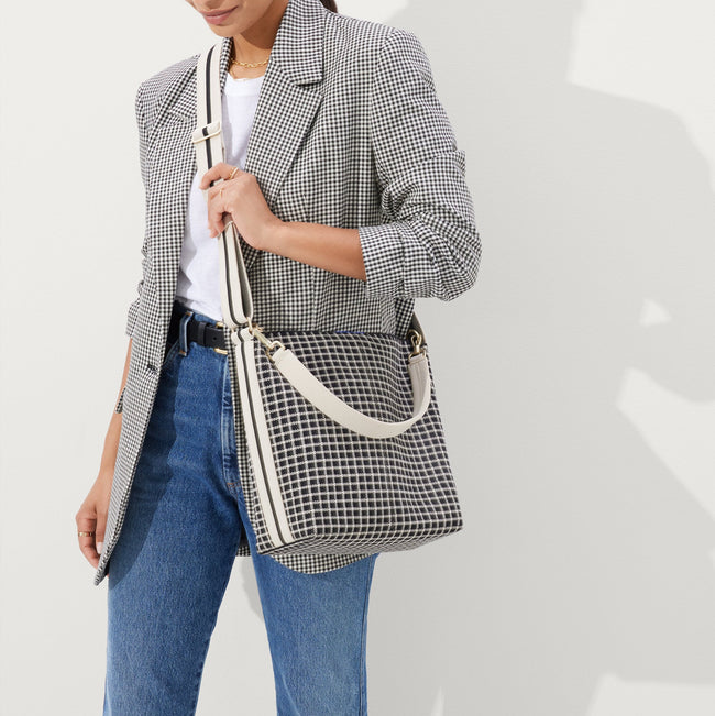 The Mini Zip Bucket in Black & Ivory Grid, carried over the shoulder of a female model, shown from the front.