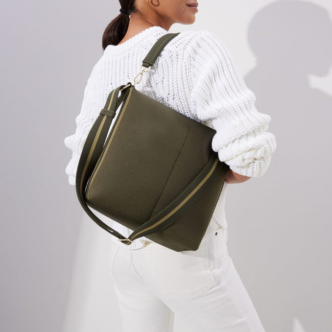 The Mini Zip Bucket in Cypress, carried over the shoulder of a female model, shown from the front.