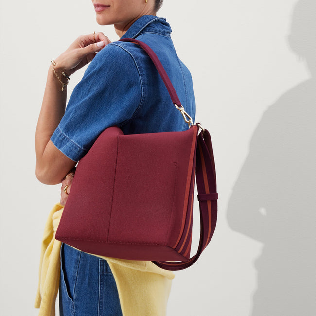 hover | The Mini Zip Bucket in Malbec Red, carried over the shoulder of a female model, shown from the back.