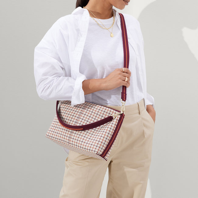 hover | The Daily Crossbody in Malbec Grid, worn as a crossbody by a female model, shown from the front.