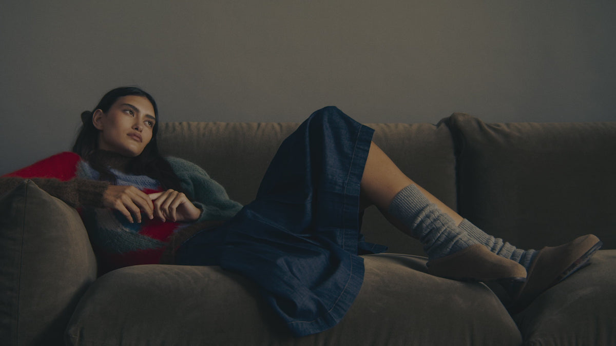 Video of a woman sitting down, wearing The Penny Clog in Dove. With text overlay "Rothys" 