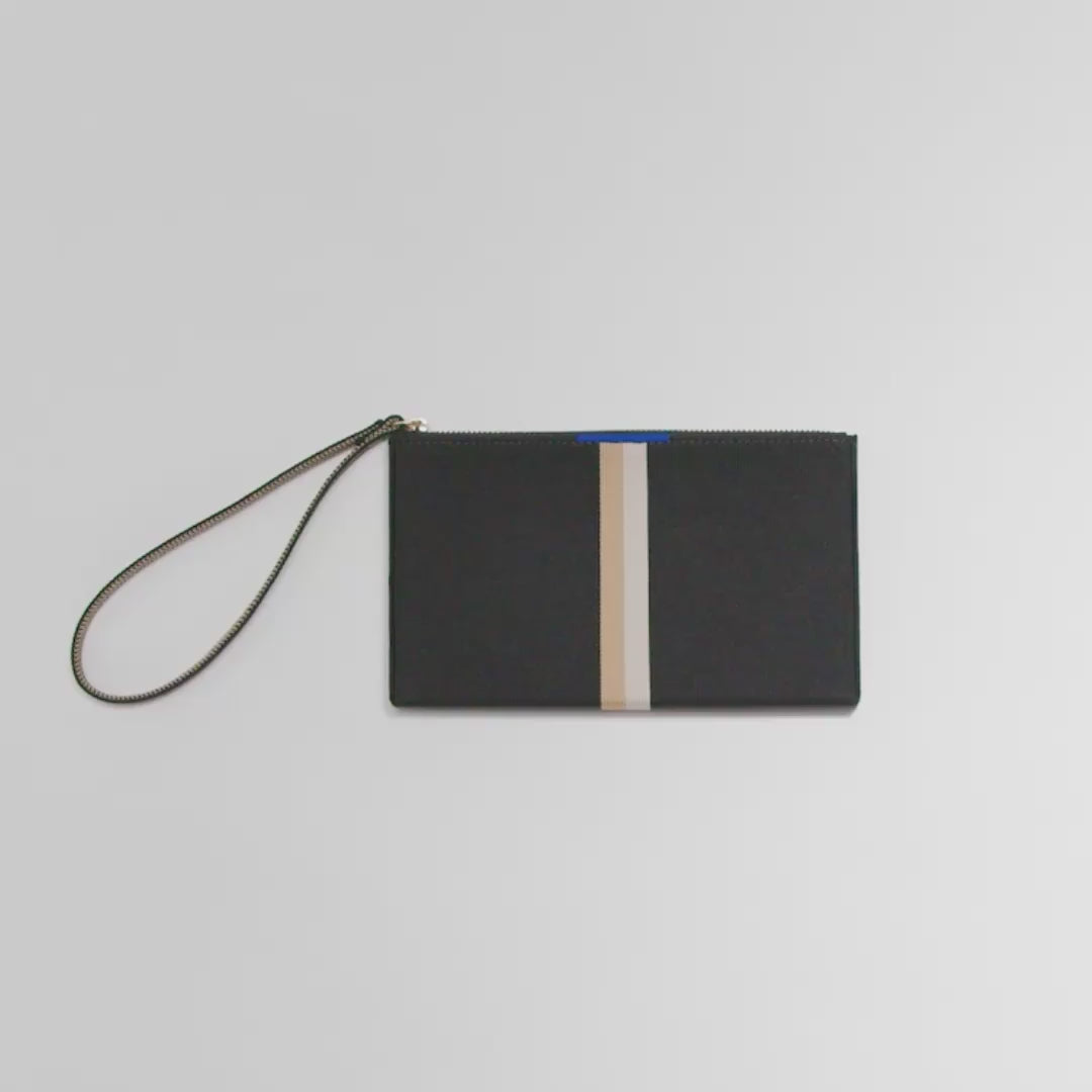 The Wallet Wristlet in Black Portobello Stripe shown packed with cards, an iPhone, cash, chap stick and keys. A female model then zips it closed and carries it out of frame.