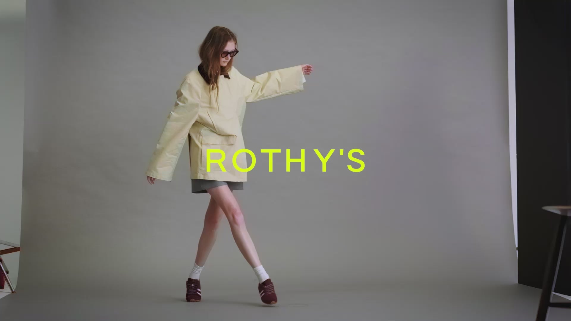 A woman walking around wearing The Ivy Sneaker in Syra, with Rothy's logo in yellow. 