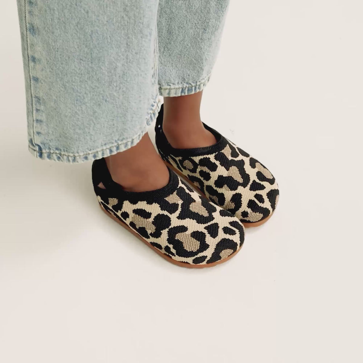 model | An alternate image of a model walking in The Kids Clog in Desert Cat and showing different angles of the shoes. 