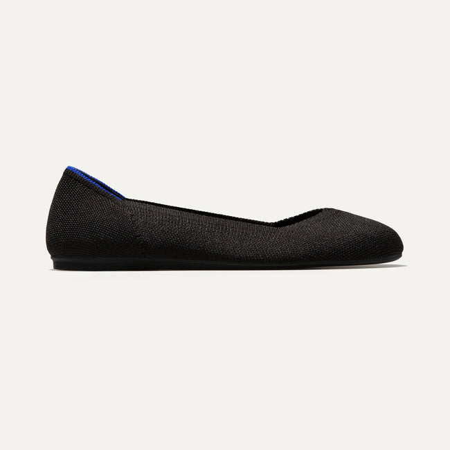The Flat round toe shoe in Black Solid shown from a side view showing the outsole.