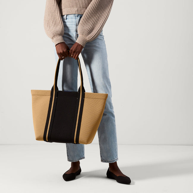 An alternate view of The Essential Tote in Camel and Black on a model.