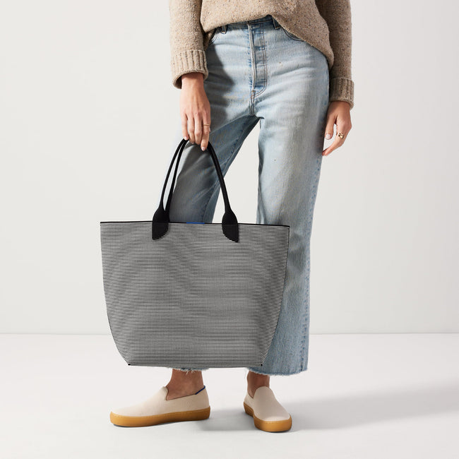 An alternate view of model holding The Lightweight Tote in Black & White Stripe.