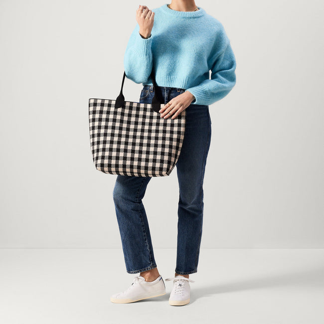 An alternate view of model holding The Lightweight Tote in Black & Canvas Gingham.