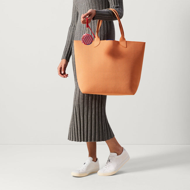 An alternate view of model holding The Lightweight Tote in Clementine.