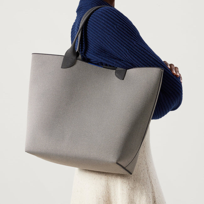 Model holding The Lightweight Tote in Iron Grey.