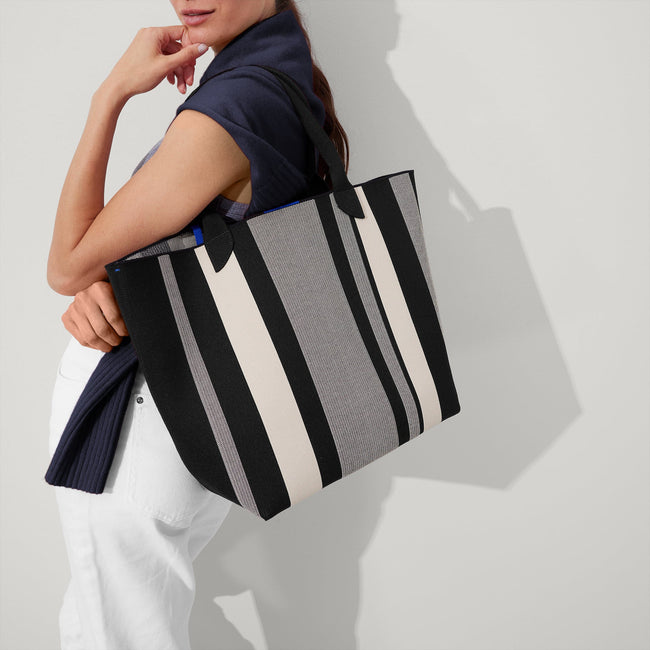 hover | Model holding The Lightweight Tote in ivory Rugby Stripe.