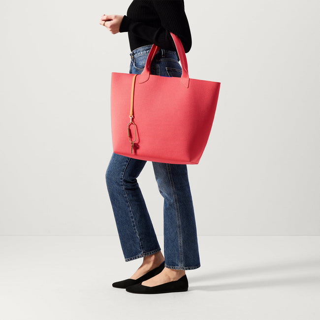 An alternate view of model holding The Lightweight Tote in Ruby Grapefruit.