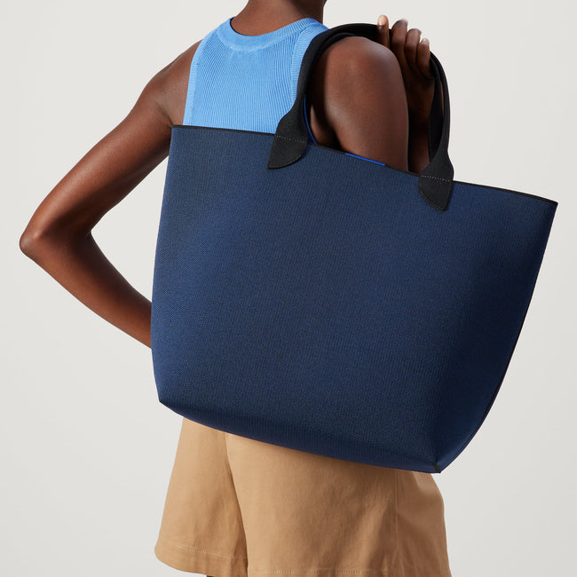 Model holding The Lightweight Tote in Sapphire and Onyx.