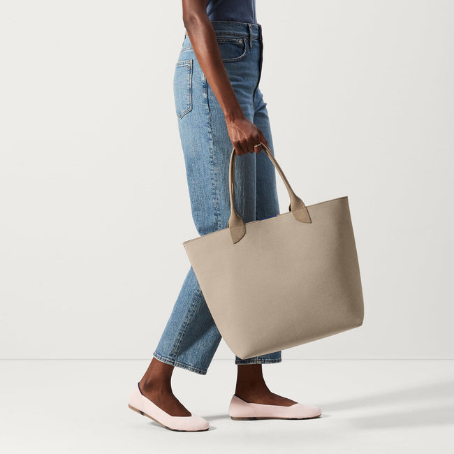 An alternate view of model holding The Lightweight Tote in Soft Sesame.