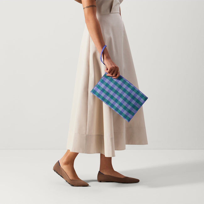 An alternate view of a model holding The Wristlet in Blueberry Gingham. 