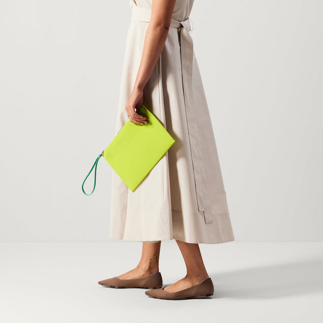 An alternate view of a model holding The Wristlet in Citrus. 