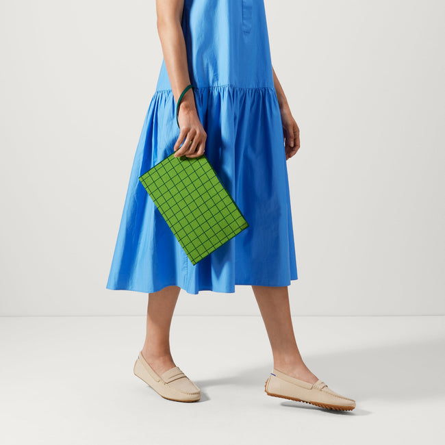An alternate view of a model holding The Wristlet in Leaf Green Windowpane.