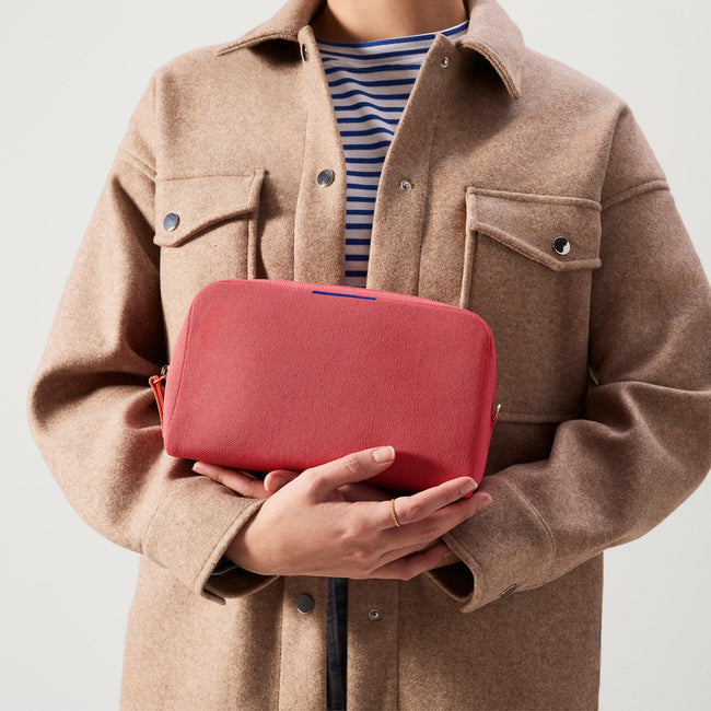 hover | The Universal Pouch in Ruby Grapefruit held by model.