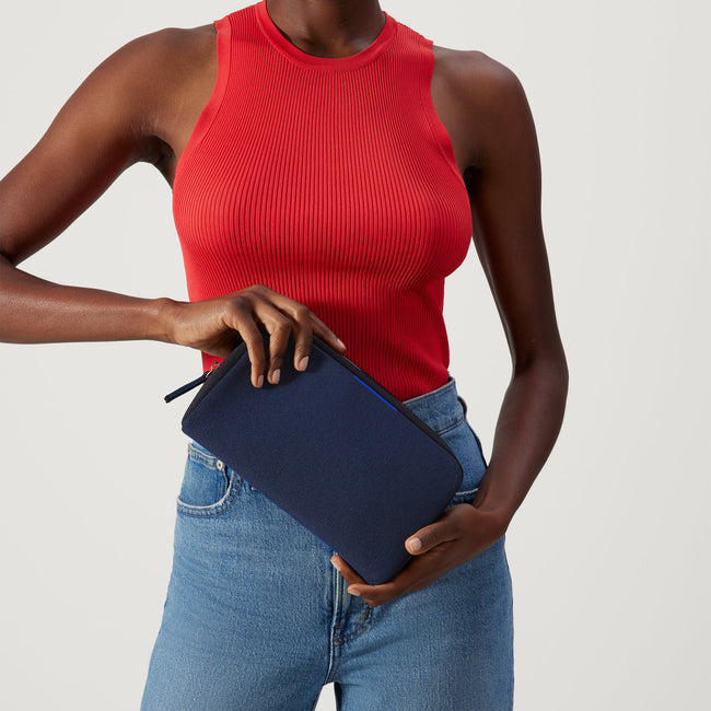 The Universal Pouch in Sapphire and Onyx held by female model.