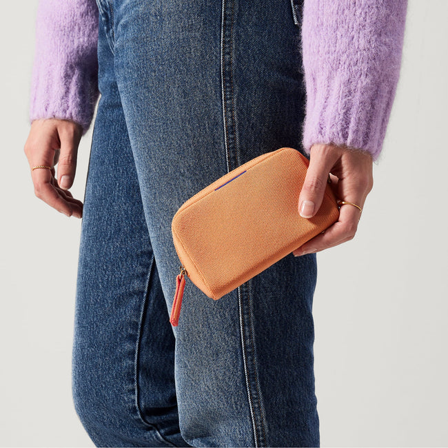 hover | The Mini Universal Pouch in Clementine held by model.