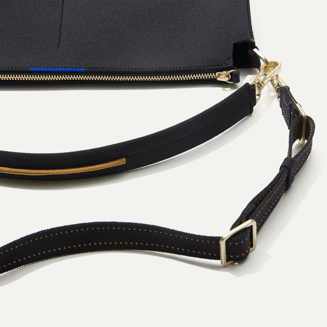 The Daily Crossbody Bag in Ink and Ivory lying flat, shown at a diagonal view from the left.