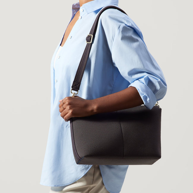 The Daily Crossbody in Ink and Ivory, carried over the shoulder of a female model.