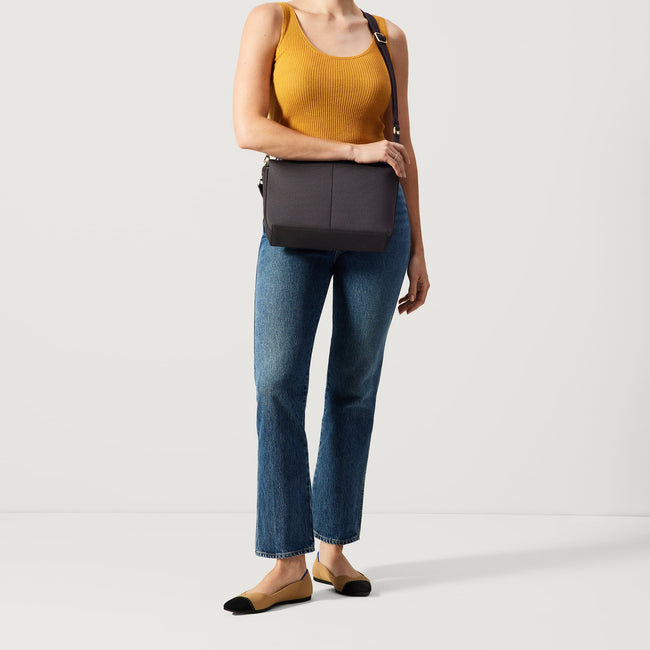 The Daily Crossbody in Ink and Ivory, worn as a crossbody by a female model, shown from the front.
