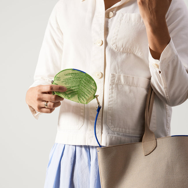 An alternate view of model holding The Demi Pouch in Palm Leaf.
